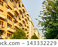 Modern apartment building facade with balconies and green trees 143332229
