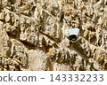 Modern White Broken CCTV Surveillance Camera Mounted on Ancient Textured Stone Wall 143332233