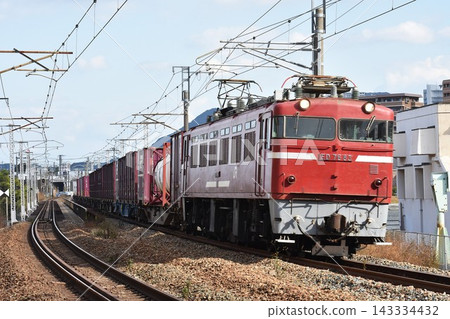 一輛電力機車和一列貨運列車正在鐵軌上行駛。 一輛電力機車和一列貨運列車正在鐵軌上行駛。 143334432