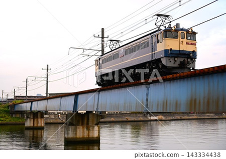 一輛電力機車和一列貨運列車正在鐵軌上行駛。 一輛電力機車和一列貨運列車正在鐵軌上行駛。 143334438