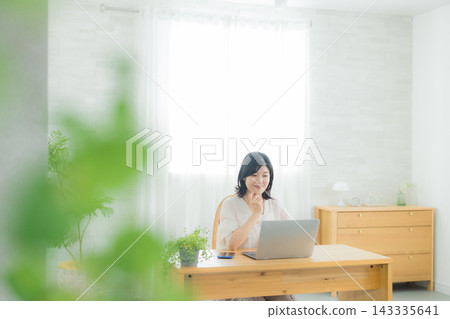 A woman looking at a computer in the living room A woman looking at a computer in the living room 143335641