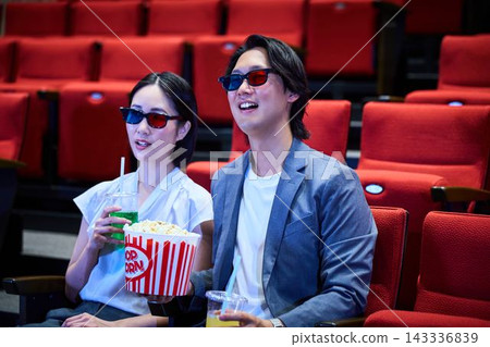 一對情侶戴著3D眼鏡在電影院享受電影約會。 一對情侶戴著3D眼鏡在電影院享受電影約會。 143336839