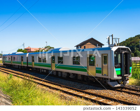 一列本地火車行駛在藍天和風景中。 一列本地火車行駛在藍天和風景中。 143339052