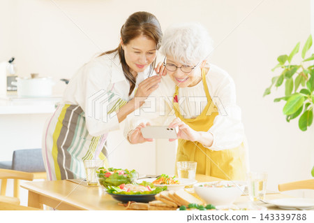 兩位日本老年婦女用智慧型手機拍攝桌上的食物。 143339788