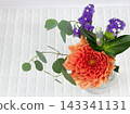 An arrangement of orange dahlias and eucalyptus in a glass bottle. 143341131