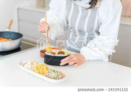 一位女性(母親、妻子、家庭主婦)在廚房打包午餐盒。 一位女性(母親、妻子、家庭主婦)在廚房打包午餐盒。 143341132