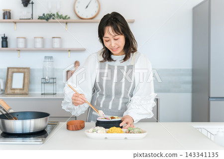一位女性(母親、妻子、家庭主婦)在廚房打包午餐盒。 一位女性(母親、妻子、家庭主婦)在廚房打包午餐盒。 143341135