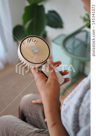a person holding a portable mini USB handheld fan a person holding a portable mini USB handheld fan 143341872