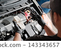 Close-up of a mechanic's hands as they change and inspect the engine oil in a car. 143343657
