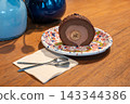 Chocolate Banana Roll Cake Slice on Colorful Plate with Spoons on Wooden Table 143344386