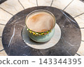 A cup of frothy coffee on a marble table 143344395
