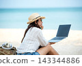 Lifestyle freelance woman using laptop working on the beach 143344886