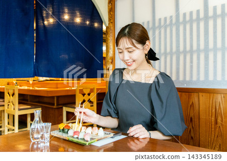 一位年輕女子獨自在壽司店享用午餐 143345189