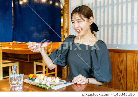 一位年輕女子獨自在壽司店享用午餐 143345190
