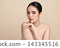 A beautiful young Asian woman with clean, fresh skin against a beige background. Skincare, facial treatment, cosmetology, beauty, and spa. An elegant portrait of an Asian woman. 143345516