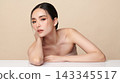 A beautiful young Asian woman with clean, fresh skin against a beige background. Skincare, facial treatment, cosmetology, beauty, and spa. An elegant portrait of an Asian woman. 143345517