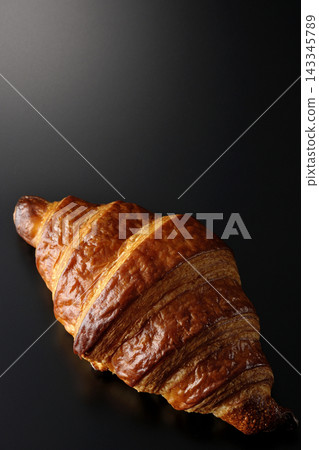 A croissant photographed against a black background. A croissant photographed against a black background. 143345789