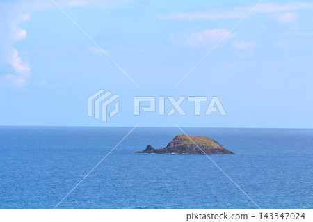 一座荒島漂浮在湛藍的天空和廣闊的地平線上。 143347024