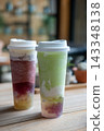 A glass of green grape tea with bubble pop, and a grape tea with chewy jelly, with cheese foam 143348138