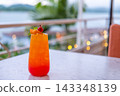 Close up view of cocktail, with slice of orange and cherry, on the table with sea view bokeh background 143348139