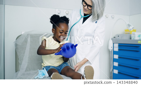 Pediatrician playing with happy child during checkup Pediatrician playing with happy child during checkup 143348840