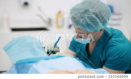 Surgeon performing operation on patient in hospital setting Surgeon performing operation on patient in hospital setting 143348899
