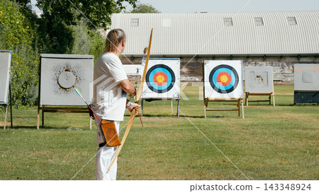 Man practicing archery aiming at outdoor targets Man practicing archery aiming at outdoor targets 143348924