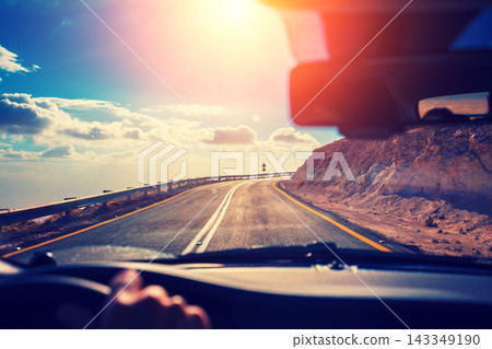Driving a car on the mountain road in the desert. View of sandstone mountains through the windscreen. The road from Arad to the Dead Sea. Israel Driving a car on the mountain road in the desert. View of sandstone mountains through the windscreen. The road from Arad to the Dead Sea. Israel 143349190