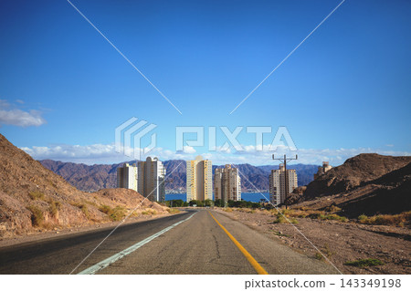 Cityscape on a sunny day. Driving a car on the road in the desert. The way to Eilat. View the beautiful mountain landscape and the city of Eilat from the windscreen. Israel Southern Israel Cityscape on a sunny day. Driving a car on the road in the desert. The way to Eilat. View the beautiful mountain landscape and the city of Eilat from the windscreen. Israel Southern Israel 143349198