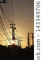 A telephone pole and the silhouette of the setting sun 143349706