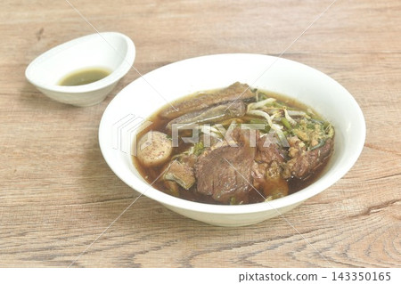 boiled spicy braised beef meat and tendon topping meatball couple bean sprout with morning glory in black herb soup on bowl dipping spicy sour sauce boiled spicy braised beef meat and tendon topping meatball couple bean sprout with morning glory in black herb soup on bowl dipping spicy sour sauce 143350165