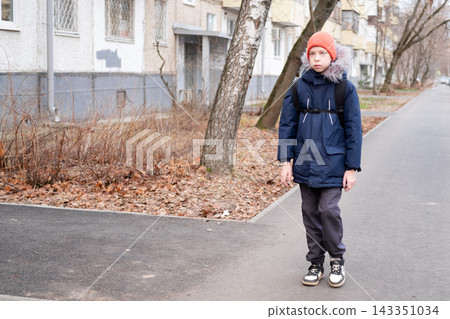 Boy student with backpack leaving apartment building entrance and walking to school, independent child concept Boy student with backpack leaving apartment building entrance and walking to school, independent child concept 143351034