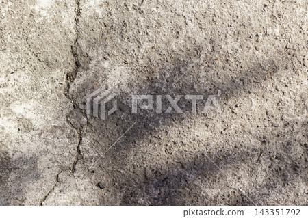 Overhead shot of a rough concrete floor with a distinct vertical crack and soft dark shadow cast across the textured surface, suitable as background. High Quality Photo 143351792