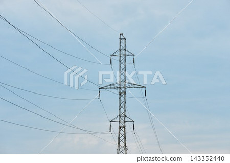 Medium shot of a metal transmission pylon with power cables and insulators isolated against a light blue sky 143352440