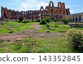 Wide Dynamic Shot of Ancient Roman Amphitheatre of El Jem with Grassy Foreground and Archways 143352845