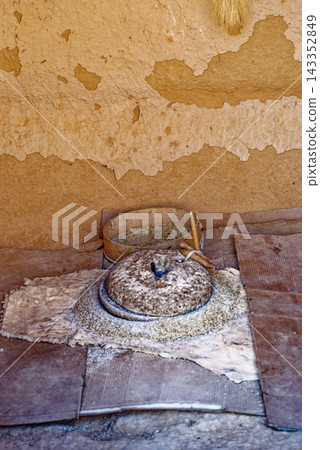Traditional Stone Hand Quern Mill with Grain Sieve Inside Berber Mud Brick Dwelling Traditional Stone Hand Quern Mill with Grain Sieve Inside Berber Mud Brick Dwelling 143352849