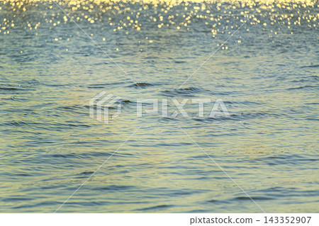 Calm blue water surface with gentle waves and golden sunlight reflections. Calm blue water surface with gentle waves and golden sunlight reflections. 143352907