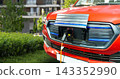 Close up of electric SUV car front inlet with a connected charging cable. 143352990