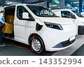 A courier removing packages from the modern electric van. The vehicle is plugged into a charging point 143352994