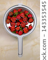 Fresh ripe strawberries in a plastic colander on a marble countertop, top view. 143353545