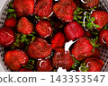 Close up of ripe strawberries soaking in water inside a colander.  143353547