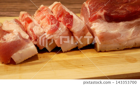 Pieces of pork lard with meat sliced and arranged on a wooden cutting board in the kitchen.  143353700