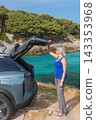 Woman is holding operating the automatic trunk closing mechanism in her vehicle in nature. 143353968