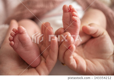 Mother Holding Tiny Newborn Baby Feet in Her Hands Conceptual Family Photo 143354212