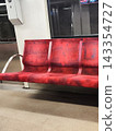 Subway car interior. Red cushioned seats on a Warsaw metro train feature a pattern. The seating arrangement is divided into three sections, with metal armrests 143354727