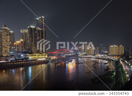 A vibrant red arch bridge spans a tranquil, foggy river framed by a multi-layered skyline of illuminated modern towers. Golden city reflections turn the water into a glowing ribbon of light. Historic A vibrant red arch bridge spans a tranquil, foggy river framed by a multi-layered skyline of illuminated modern towers. Golden city reflections turn the water into a glowing ribbon of light. Historic 143354743