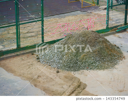 Sports court renovation site fenced with safety tape beside a goal. Recreation facility construction and grounds maintenance. Court repair work. Restricted access and public safety. Sports court renovation site fenced with safety tape beside a goal. Recreation facility construction and grounds maintenance. Court repair work. Restricted access and public safety. 143354749