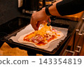 Adding shredded cheese to homemade pizza before baking 143354819