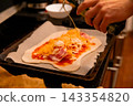 Hand Drizzling Cooking Oil Over Homemade Pizza 143354820