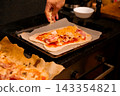 Adding cheese and toppings to homemade pizza before baking 143354821